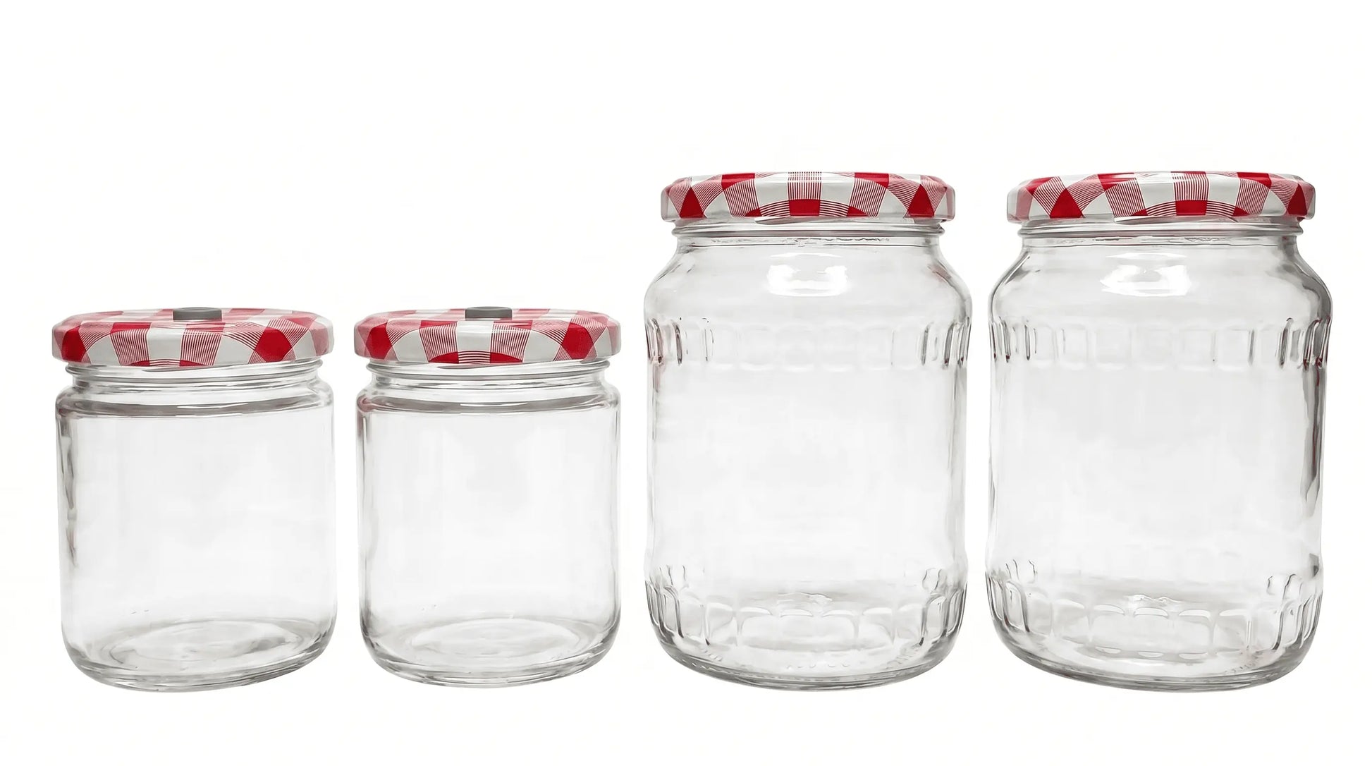 Four empty glass mushroom growing jars in varying sizes with modified red and white checkered lids for inoculation.