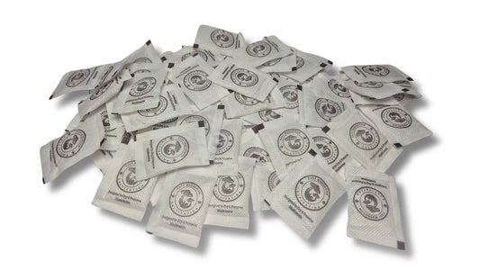 A large, scattered pile of white desiccant packets on a white surface. Every packet displays a circular logo of a mushroom and the brand name "Easy Mushroom Cultivation."