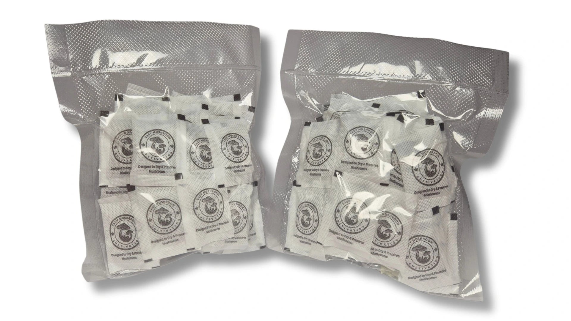 Two clear vacuum-sealed plastic bags filled with numerous small white desiccant packets. Each packet features a circular "Easy Mushroom Cultivation" logo and the text "Designed to Dry & Preserve Mushrooms."